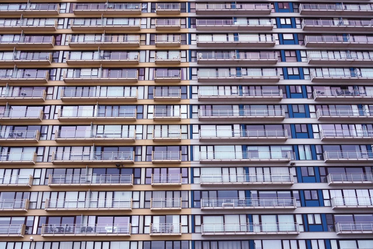 Symmetrical facade of a modern residential apartment building showcasing multiple balconies and windows.