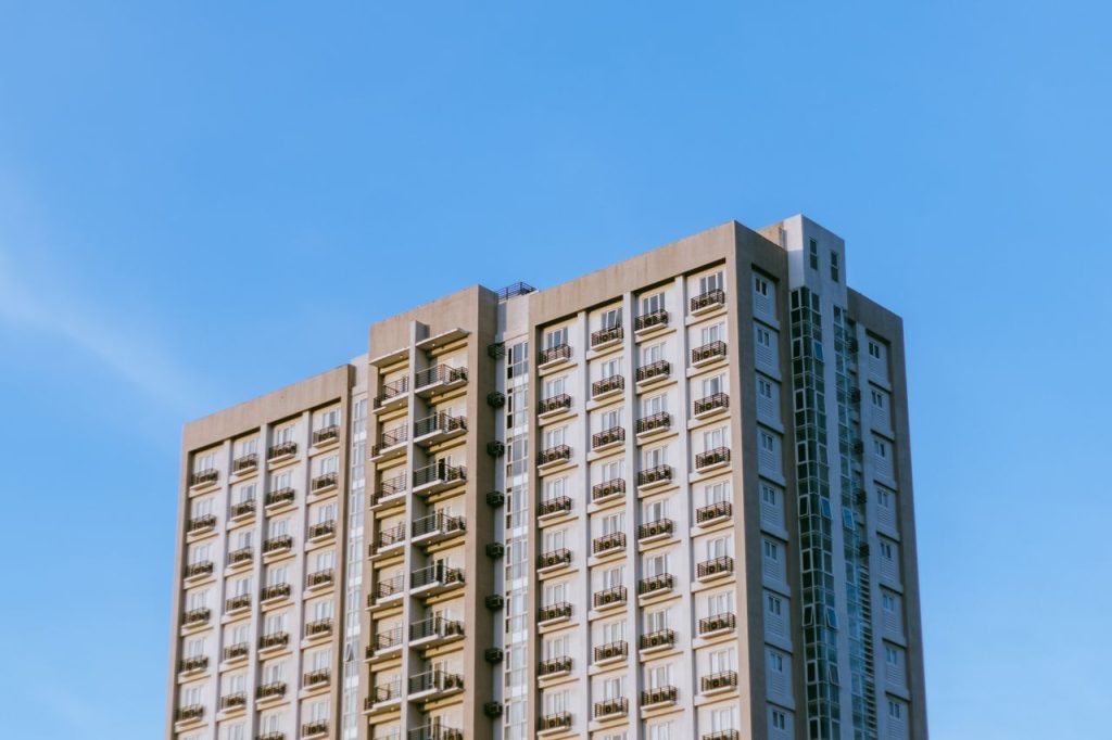 Contemporary high-rise apartment building with balconies under a clear blue sky.